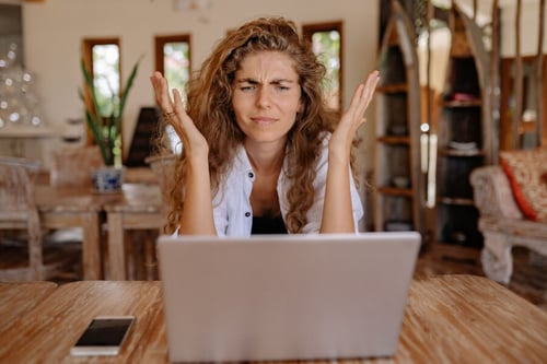 Femme visiblement stressée devant un ordinateur portable dans un salon, se demandant si un propriétaire peut annuler un bail 