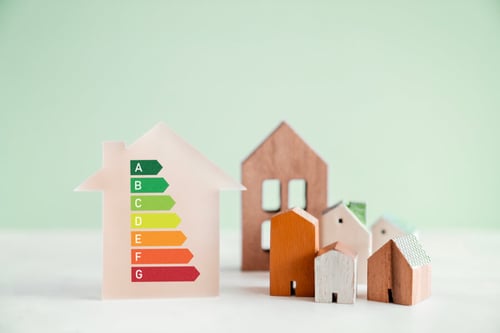Guide visuel pour comprendre le Diagnostic de Performance Énergétique DPE avec une illustration des classes énergétiques de A à G. Cette image montre une étiquette énergétique simplifiée indiquant les différentes catégories de performance énergétique, allant de la classe A en vert, la plus économe, à la classe G en rouge, la plus énergivore. À droite de l'étiquette, plusieurs maquettes de maisons en carton illustrent les types de logements concernés par ce diagnostic. Parfait pour les propriétaires bailleurs souhaitant évaluer et améliorer la performance énergétique de leur bien immobilier. Comprendre le DPE est essentiel pour respecter les réglementations et optimiser la consommation énergétique de son logement.