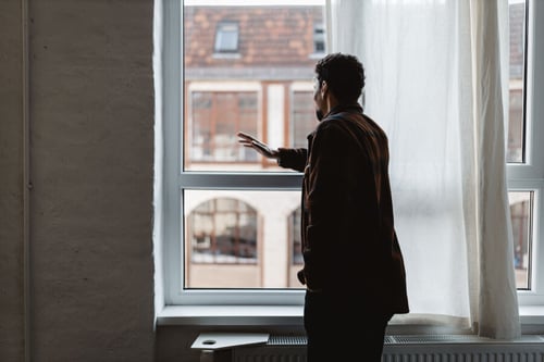 Homme ajustant le store d’une fenêtre pour améliorer le confort thermique dans un logement en location par temps ensoleillé