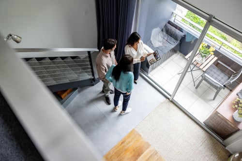 Trois personnes discutent d’un diagnostic de performance énergétique lors d’une visite immobilière dans un salon lumineux