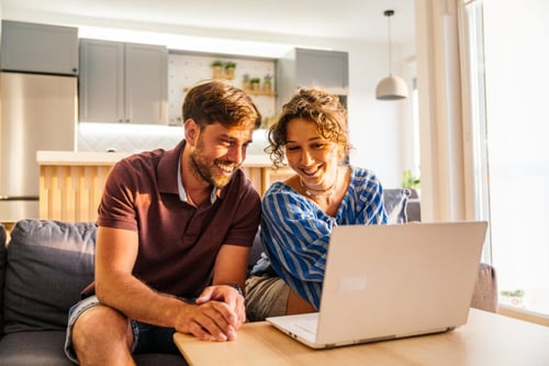 Couple souriant consultant un ordinateur portable pour un investissement locatif rentable dans un salon moderne et lumineux. L’homme et la femme analysent des données immobilières sur un site spécialisé en placements financiers et biens locatifs. Arrière-plan montrant une cuisine contemporaine équipée, évoquant l’achat d’un appartement ou d’une maison comme placement immobilier. Illustration parfaite pour un article sur les biens les plus rentables en investissement locatif, conseils en gestion de patrimoine et stratégies d’acquisition immobilière. Optimisation fiscale et recherche de rentabilité locative en milieu urbain.