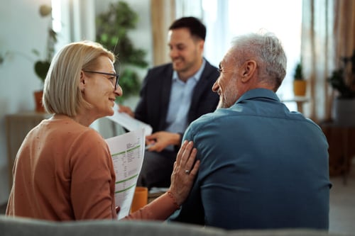 Couple de retraités discutant avec un conseiller pour préparer leur retraite via une SCI familiale dans un bureau lumineux