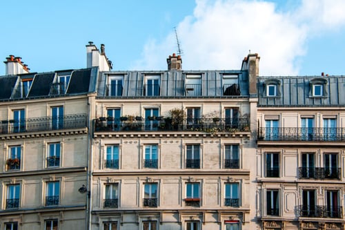 Façade typique d'immeubles parisiens en pierre de taille avec balcons en fer forgé et fenêtres à petits carreaux, illustrant un logement locatif en centre-ville susceptible d'être concerné par des litiges liés au dépôt de garantie lors de l'état des lieux de sortie. Les bâtiments de 5 à 6 étages, avec leurs toits en zinc et leurs garde-corps caractéristiques, représentent le style architectural emblématique des appartements loués à Paris, où les conflits sur la restitution du dépôt de garantie sont fréquents.