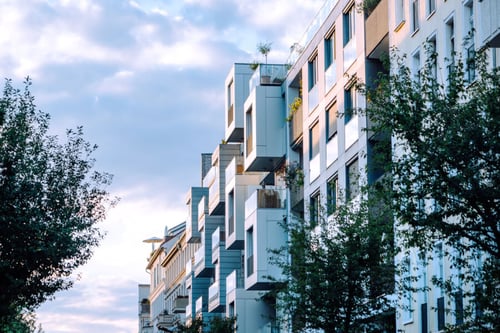  Ensemble de résidences modernes avec balcons aménagés en zone urbaine, illustrant un potentiel investissement locatif attractif pour les bailleurs privés. Les bâtiments, de style contemporain aux lignes épurées, présentent des façades claires et des espaces extérieurs optimisés avec des plantes, offrant un cadre de vie agréable pour les locataires. Idéal pour un article sur les opportunités et évolutions du statut de bailleur privé dans le secteur immobilier.