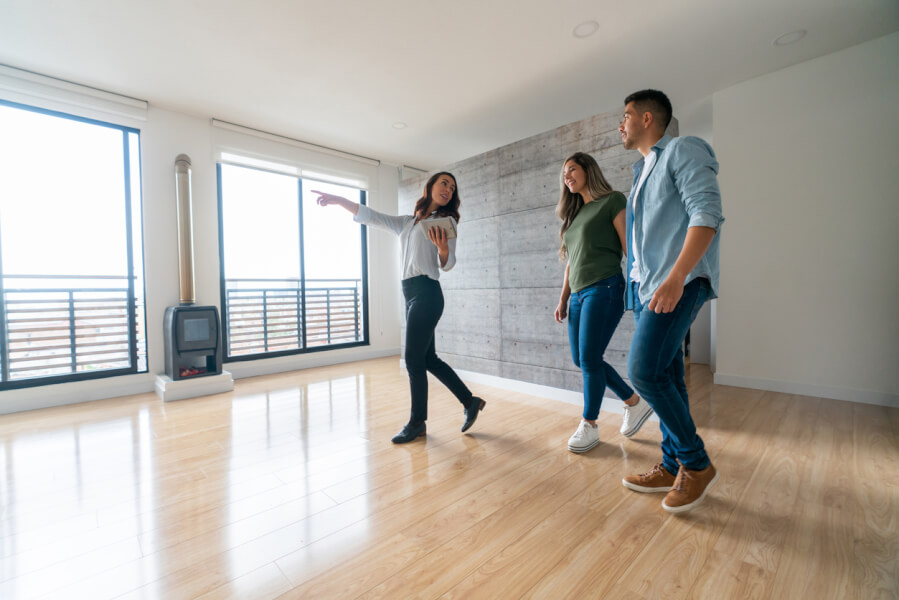 Trois personnes visitant un appartement vide avec un agent pour un contournement d’agence immobilière