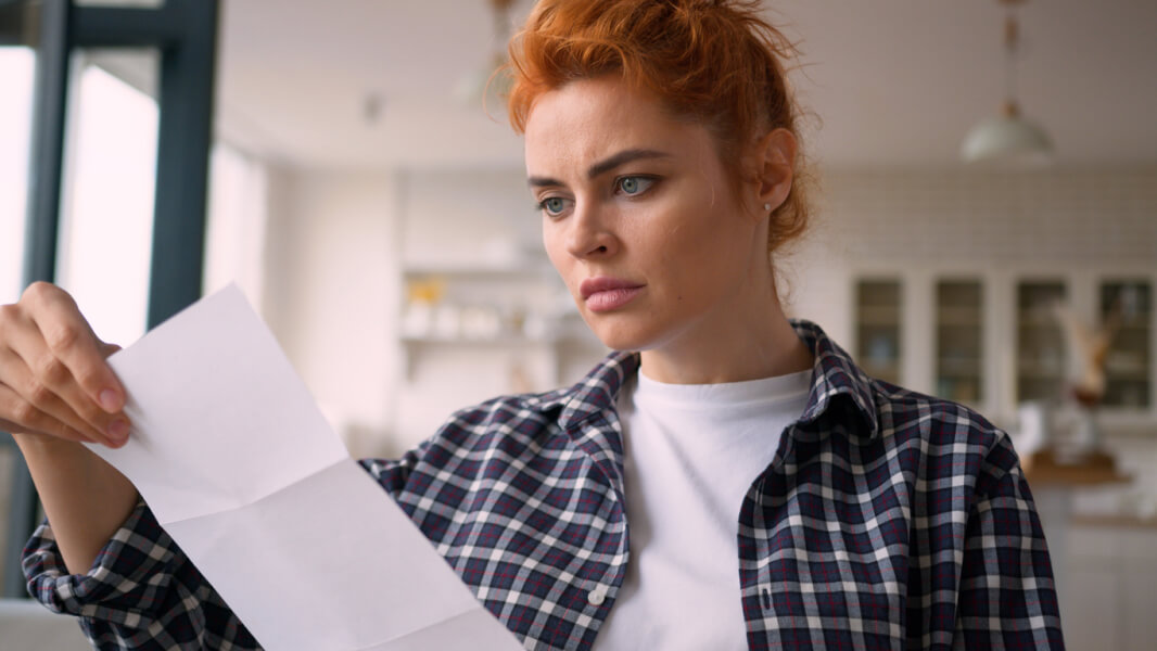 Femme examinant attentivement un avis de congé pour reprise dans une cuisine lumineuse
