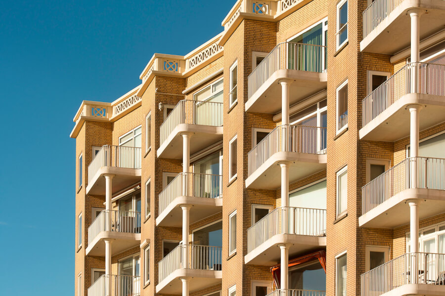 Immeuble en copropriété avec balcons et appartements en location sous un ciel bleu dégagé évoquant les droits des locataires