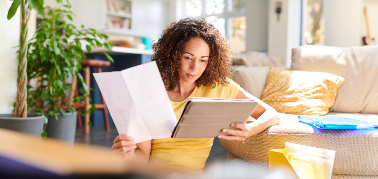 Femme locataire lisant attentivement un contrat d’assurance habitation dans un salon lumineux et cosy. Elle est assise sur un canapé avec des coussins décoratifs, entourée de plantes d’intérieur et d’une ambiance chaleureuse. À ses côtés, un ordinateur portable et des documents administratifs posés sur la table basse, illustrant la vérification des obligations liées à l’assurance habitation pour locataire. Cette scène reflète les démarches essentielles pour comprendre les garanties et responsabilités avant de souscrire une assurance logement en tant que locataire. Idéale pour accompagner un article sur les obligations d’assurance habitation pour les locataires.