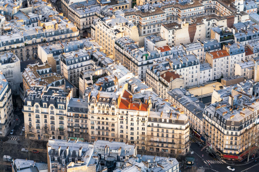 Découvrez une vue aérienne impressionnante du paysage urbain dense de Paris en 2025, illustrant l'état actuel du marché immobilier dans la capitale française. Cette image montre un quartier typique avec des immeubles haussmanniens aux toits en zinc, caractéristiques de l'architecture parisienne. Les bâtiments, majoritairement résidentiels, reflètent la forte demande en logements dans cette métropole où l'espace est limité. On observe des rues étroites, des cours intérieures et une mixité de constructions anciennes et rénovées, soulignant les défis de rénovation et de modernisation du parc immobilier parisien. Ce cliché met en avant la densité urbaine et la rareté des terrains disponibles, des facteurs clés influençant les prix et les tendances du marché immobilier à Paris en 2025. Idéal pour comprendre les enjeux de l'immobilier dans une ville en constante évolution.